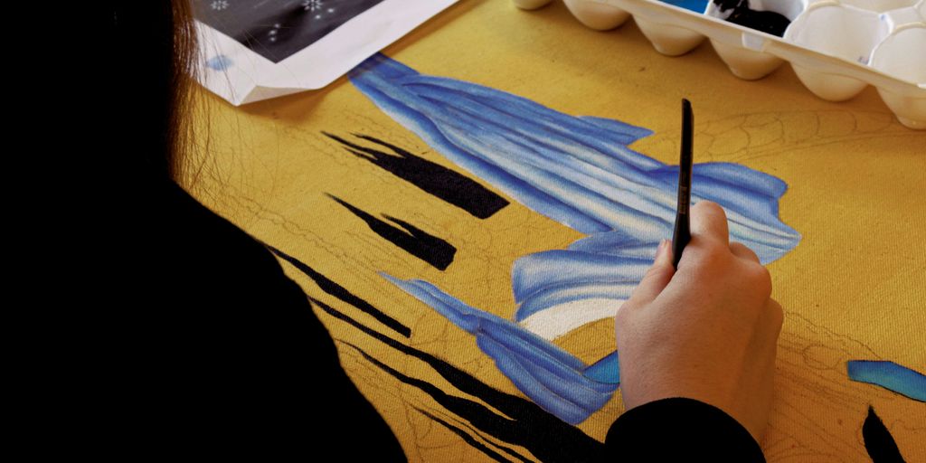 person holding black pen on blue textile